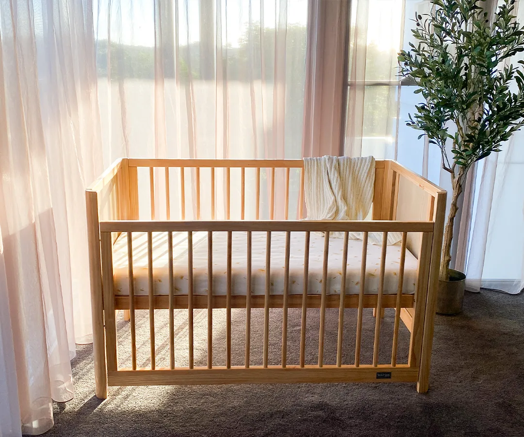 Aliya Rattan Cot viewed from the front with its timber drop side