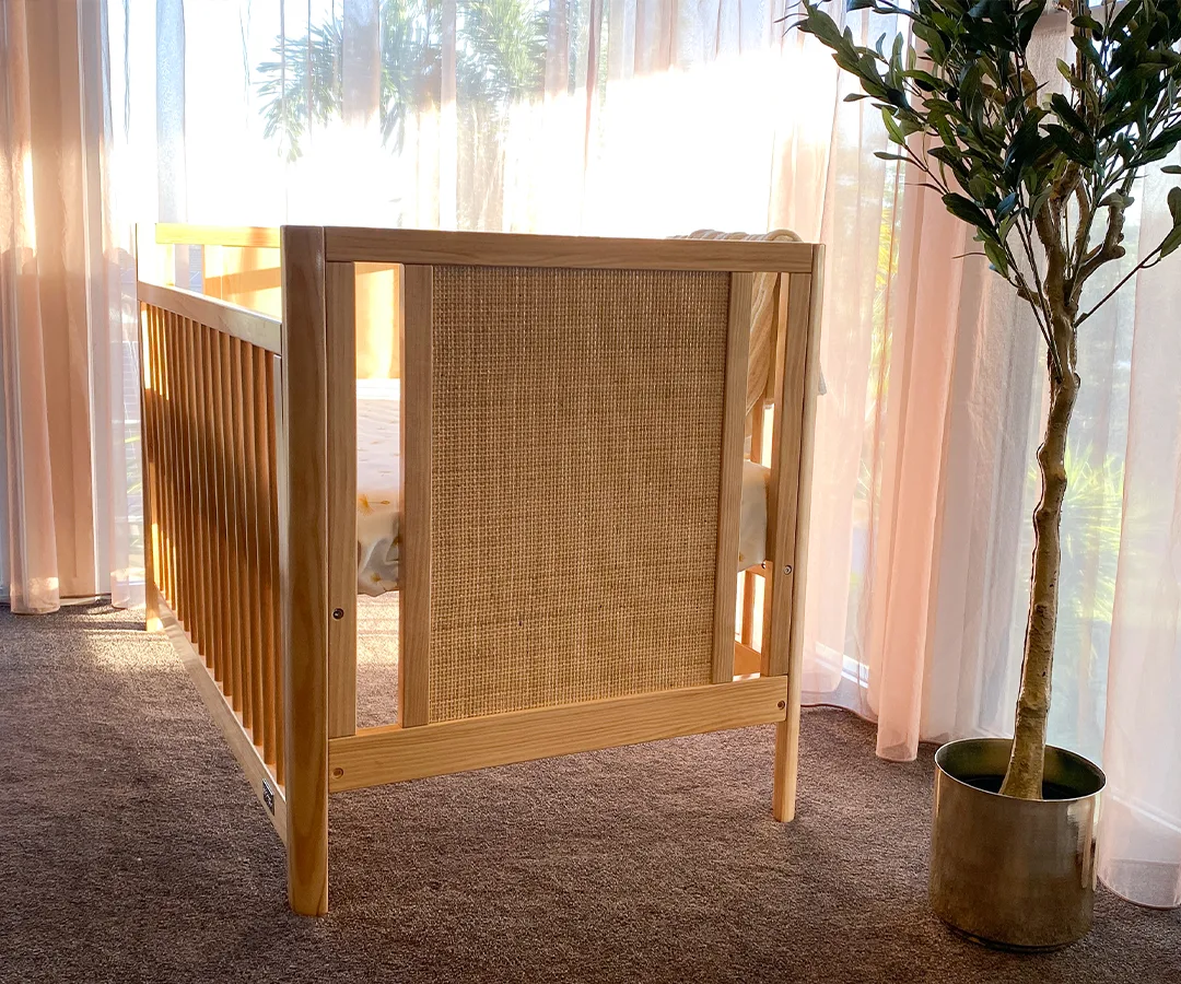 Close view of the natural woven-look end panel on the Aliya cot