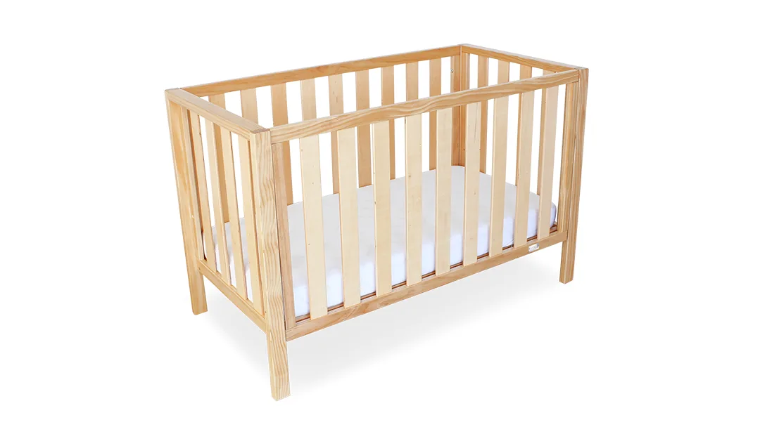 Mali Compact Cot shown beside a bed in a small room