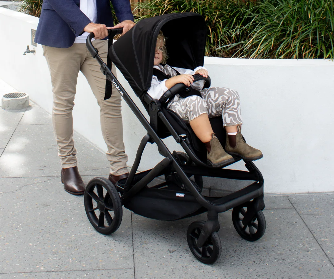 Doppio Plus stroller showing its four-wheel running gear on a paved path