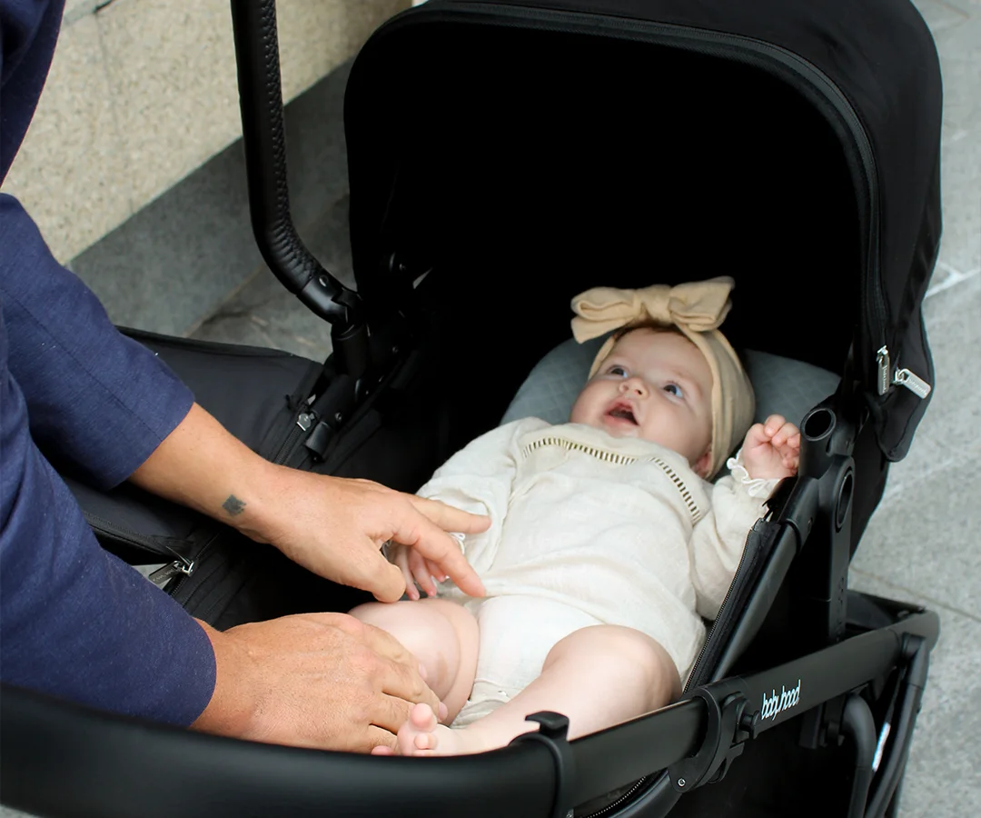 Newborn lying inside the Doppio Plus bassinet beneath its canopy