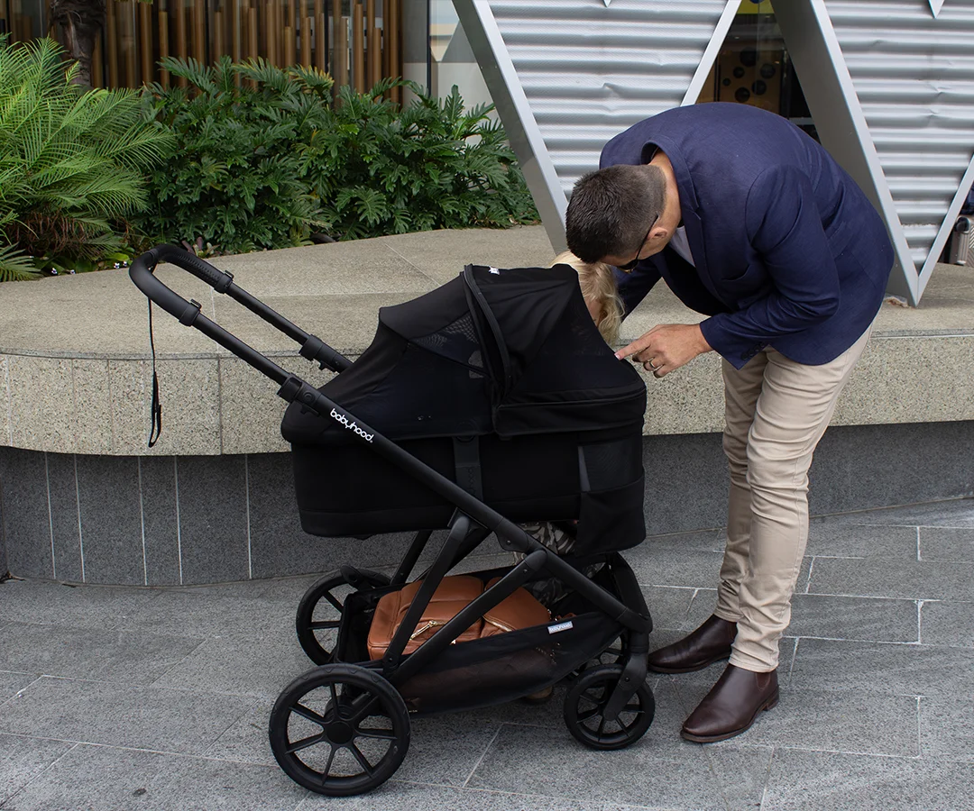 Parent attending to a baby in the Doppio Plus bassinet configuration