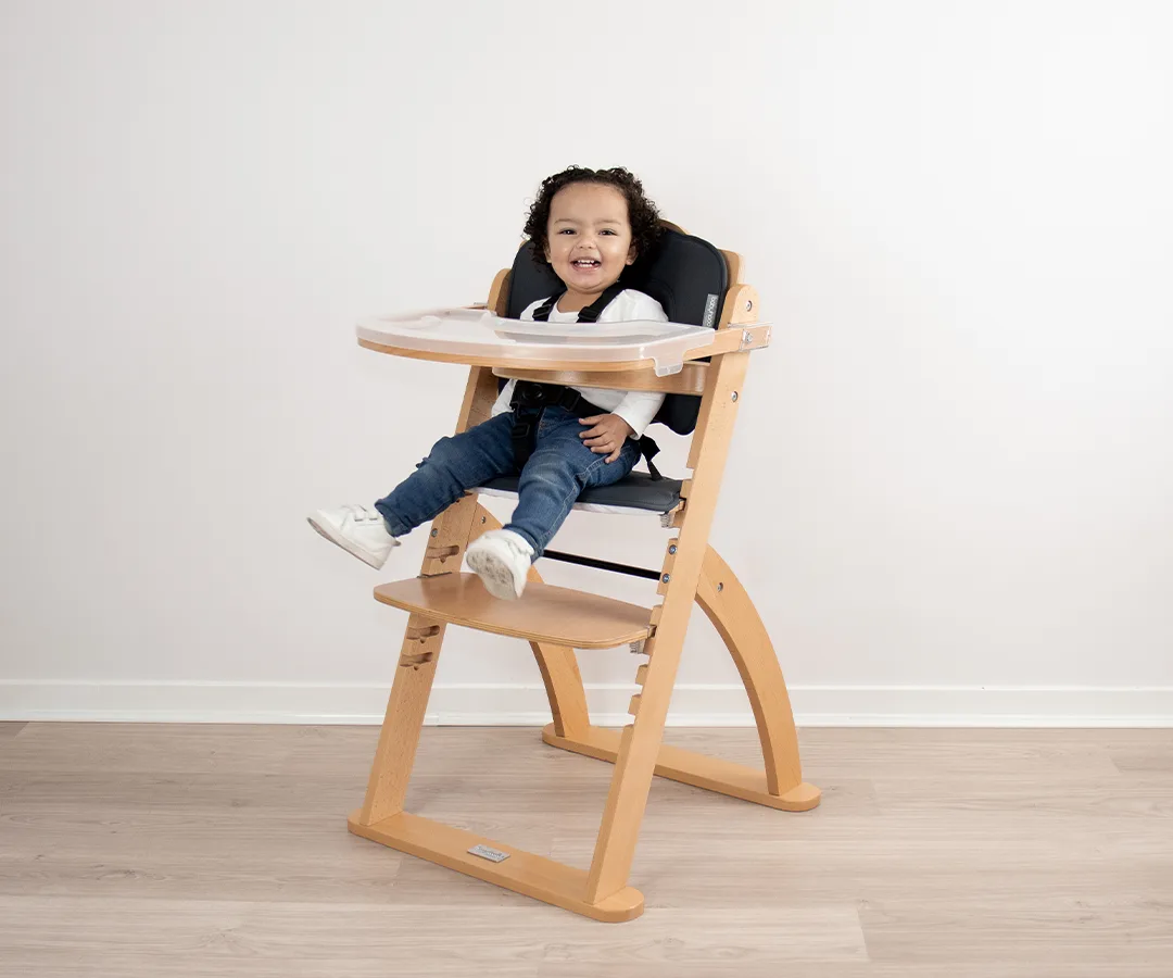 Side view of the Ava high chair showing its curved beech frame and adjustable foot plate