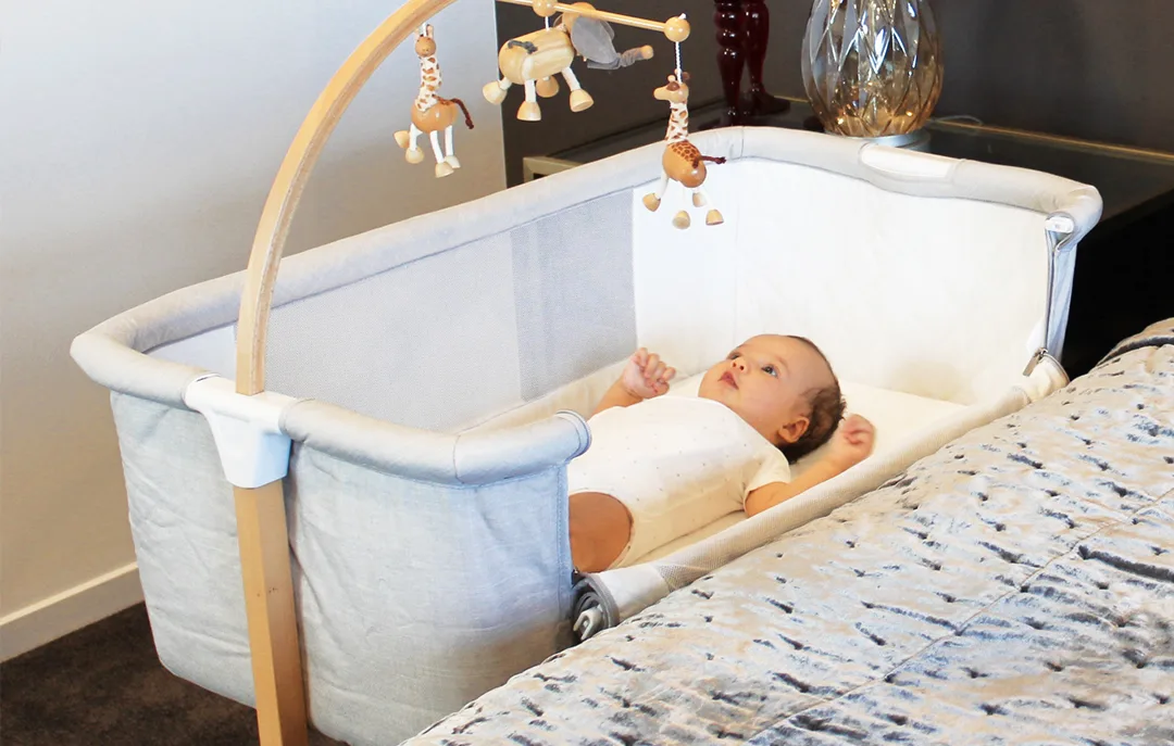Baby resting in the Kaylula cradle beside a parent